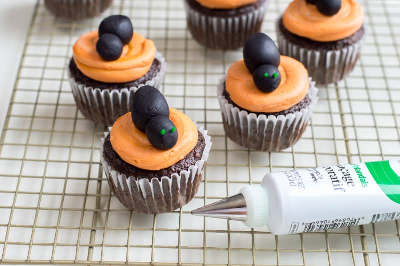 orange frosted cupcake with black fondant