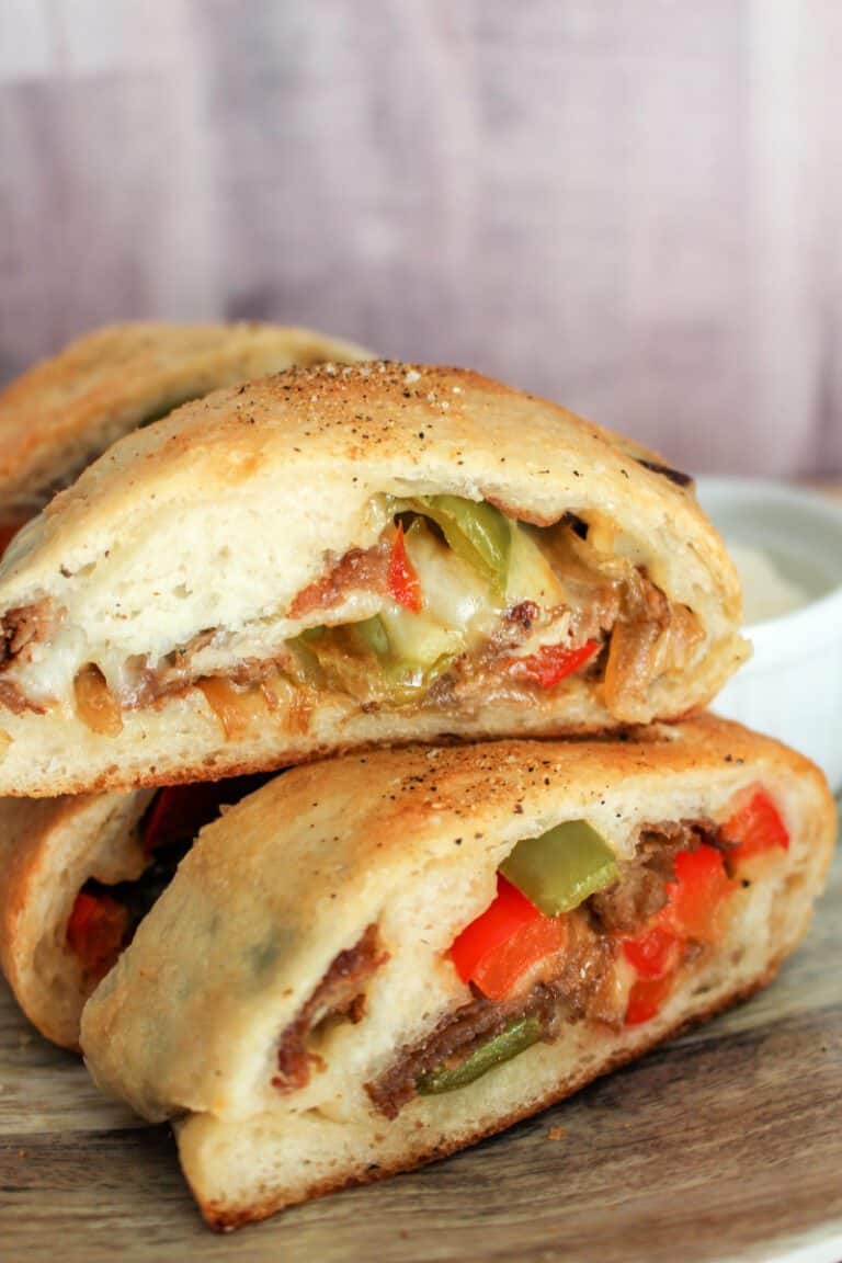 Tasty stuffed sandwich with meat, cheese, and peppers on a wooden surface.