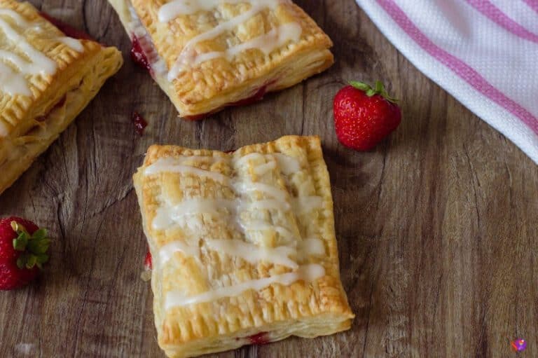 Puff Pastry Strawberry Strudel on a table with strawberries next to it