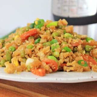 A plate of Instant Pot cauliflower fried rice with vegetables on a kitchen counter.