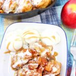 A skillet with frosted cinnamon rolls and a tempting plate of cinnamon rolls, ice cream, and caramel sauce. Next to it sits a caramel apple pull apart bread beside an apple and a fork, all arranged on a patterned tablecloth.