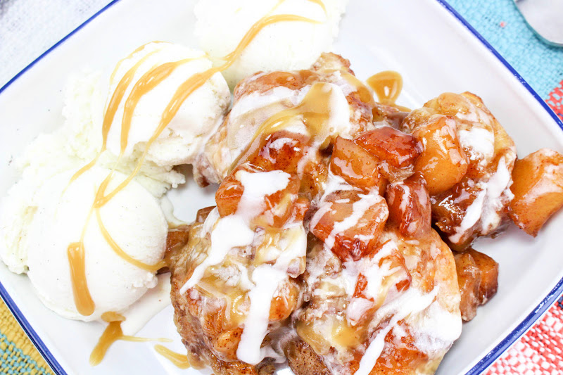A delightful caramel apple pull apart bread sits on a white plate, with vanilla ice cream scoops drizzled in rich caramel sauce for a perfect dessert pairing.