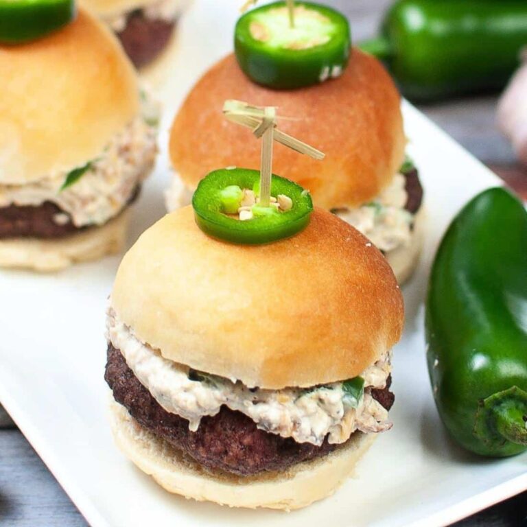 Air fryer jalapeno popper burger sliders on plate next to jalapeno peppers.