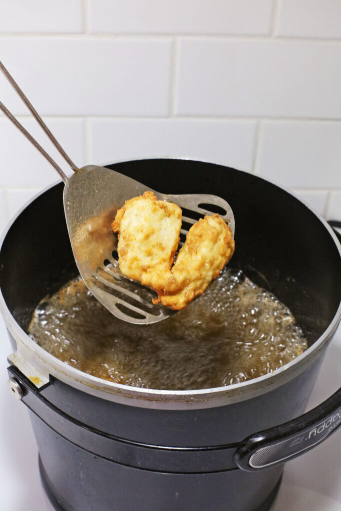 Copy Cat Chick-Fil-A Chicken Mini's 8 A battered Chick-Fil-A Chicken Mini is lifted from a pot of hot oil with a metal slotted spatula.