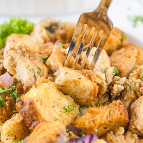 A close-up of a fork picking up a piece of savory Traeger smoked stuffing seasoned with herbs.