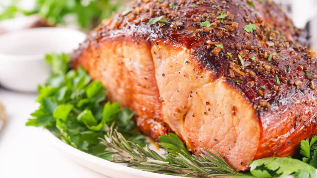 Bourbon Glazed Ham garnished with parsley on a white plate.