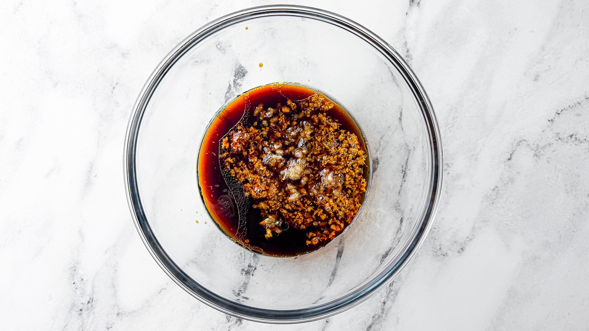 Glass bowl with teriyaki sauce ingredients mixed together on table.