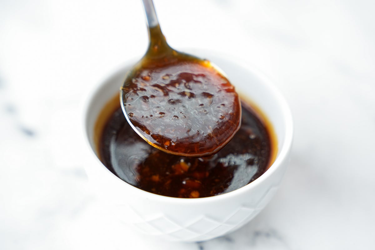 homemade teriyaki sauce in sauce bowl, dripping from spoon