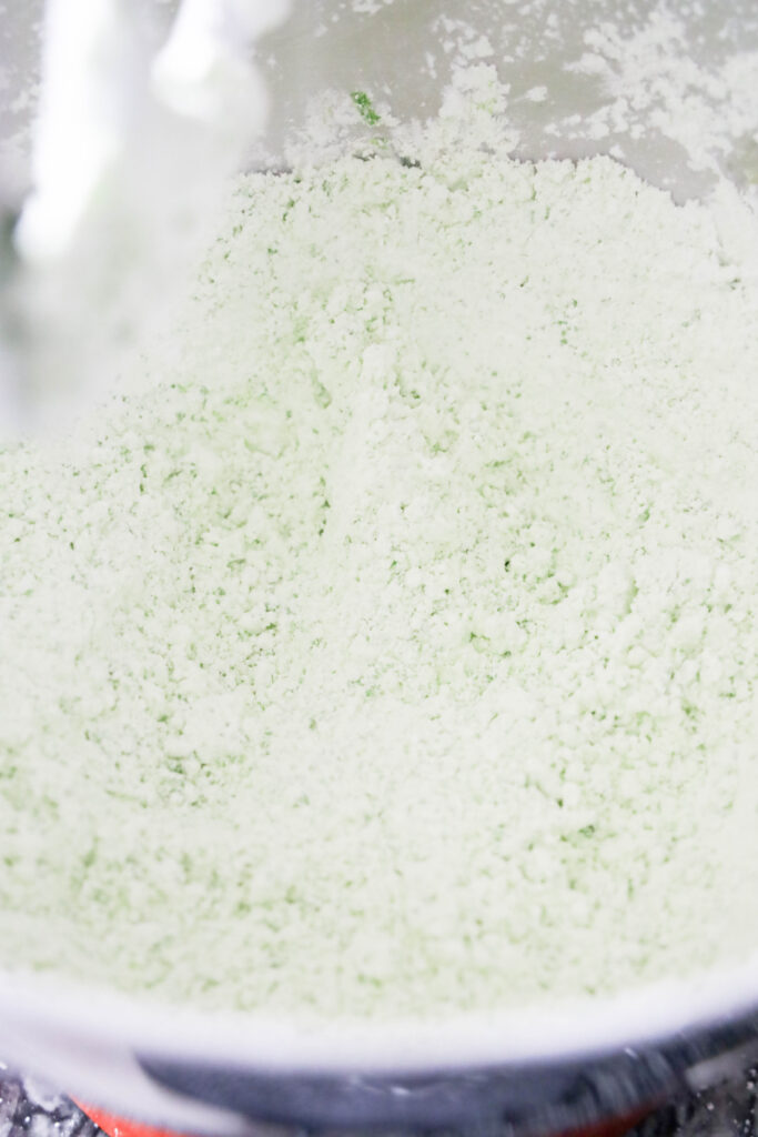 Close-up of pale green powdery mixture in a mixing bowl, reminiscent of Grinch Puppy Chow.