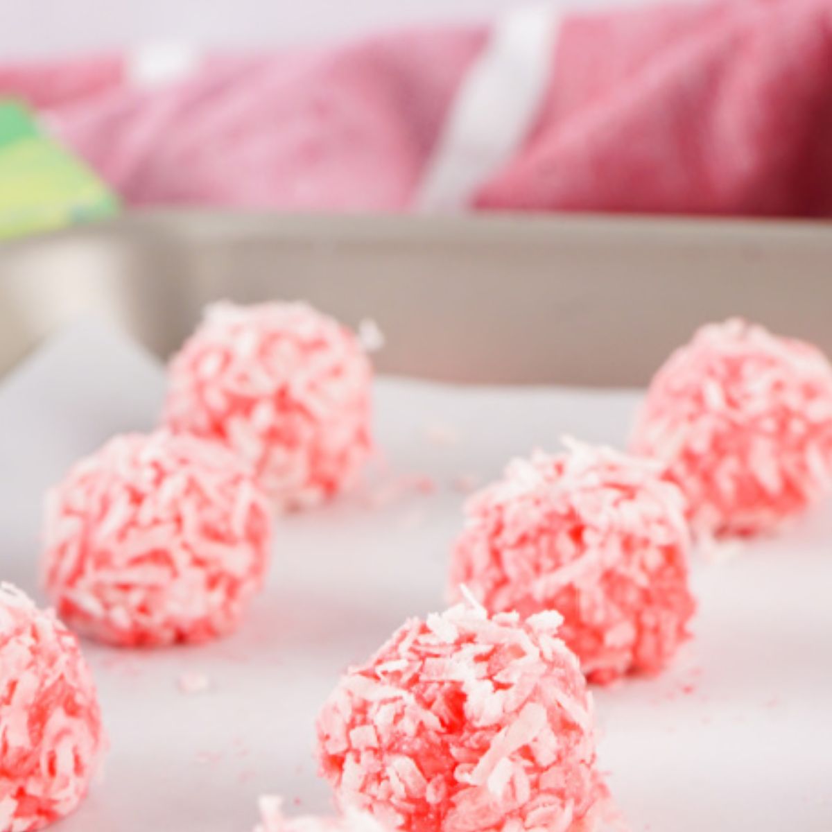 Strawberry jell-o coconut balls on baking sheet.