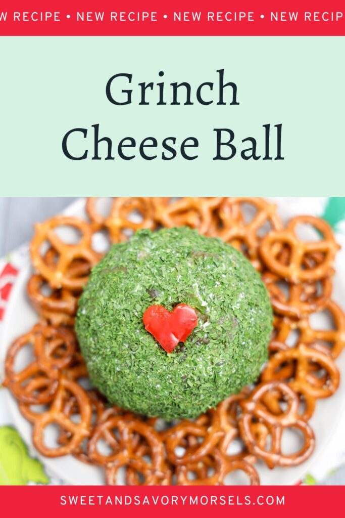 A Grinch Cheese Ball adorned with a red heart sits at the center, surrounded by crunchy pretzels on a plate.