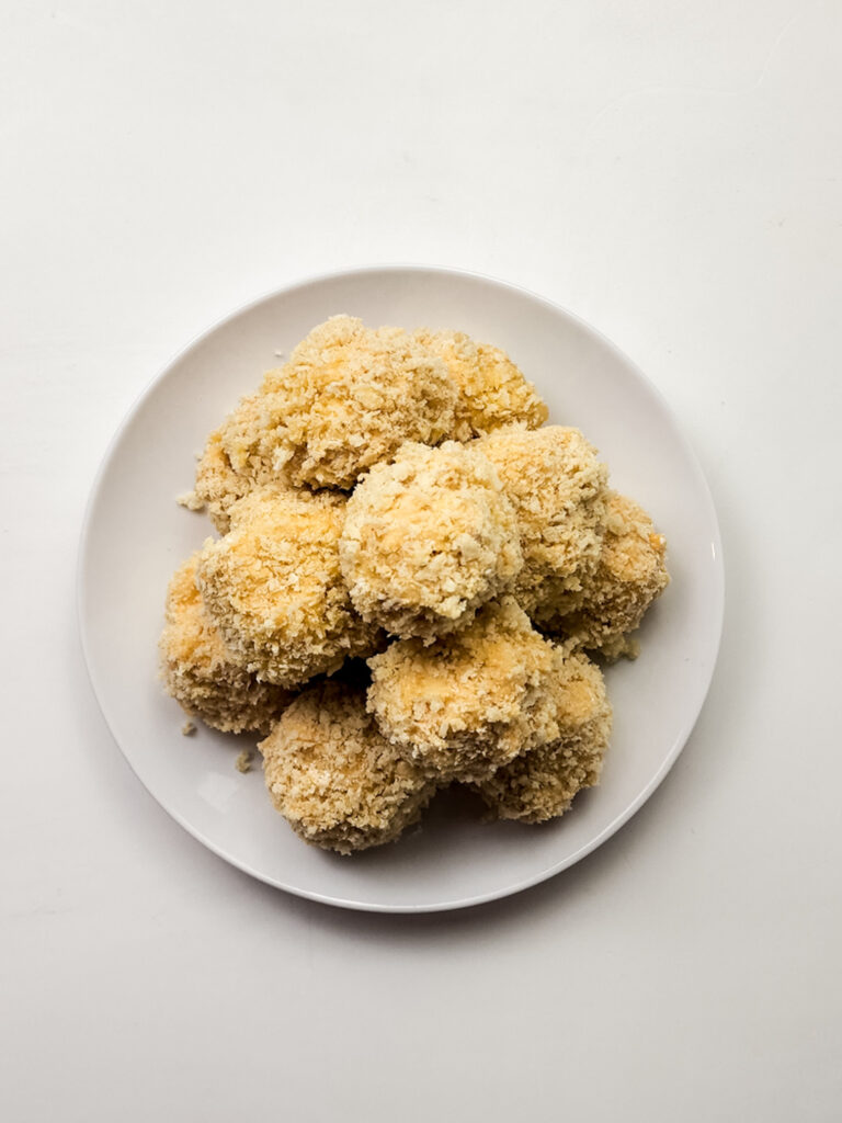 A plate of golden-brown mac and cheese bites, each deliciously deep-fried to perfection, arranged in a tempting pyramid shape.