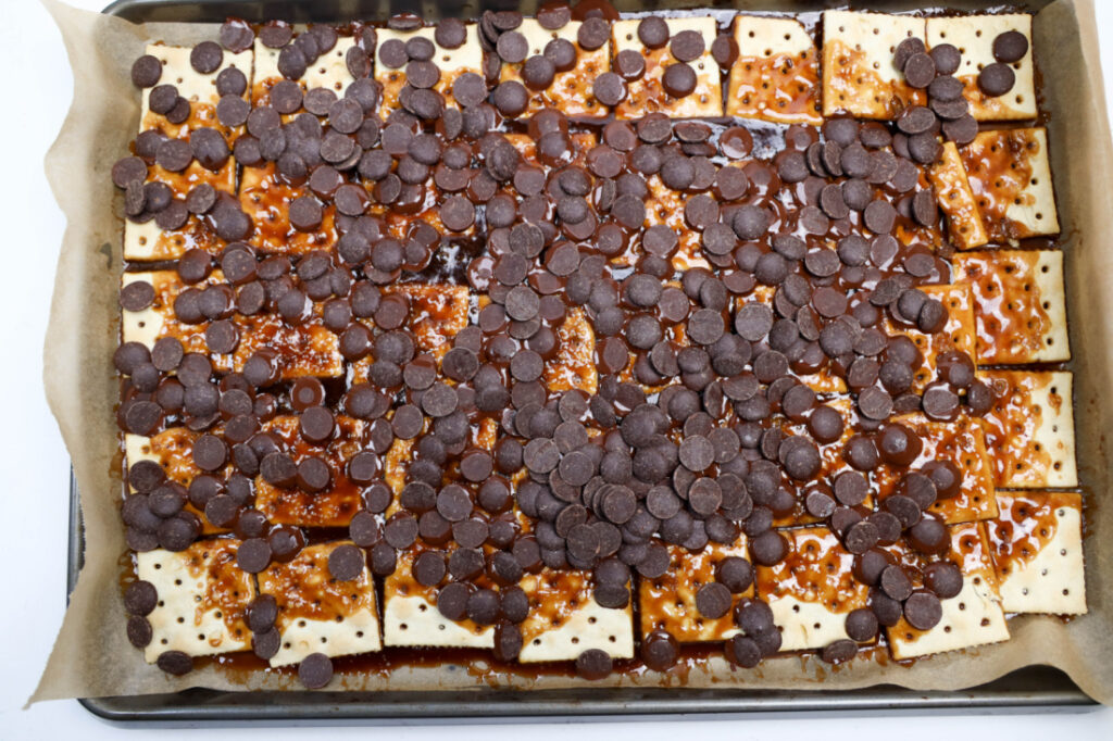 Glitter Valentine's Cracker Candy: A Sweet & Sparkly Treat 7 Valentine's Cracker Candy delights with saltine crackers topped with melted caramel and chocolate chips on a baking sheet lined with parchment paper.
