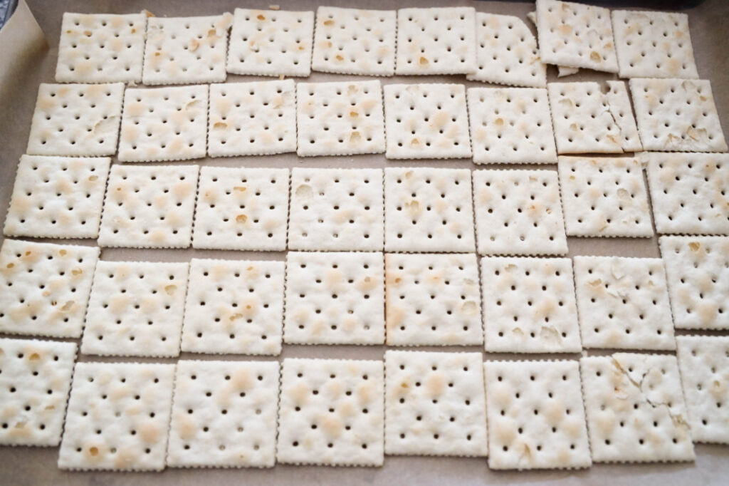 Glitter Valentine's Cracker Candy: A Sweet & Sparkly Treat 4 A grid of square saltine crackers with small holes, arranged neatly on a baking sheet, ready to be transformed into delicious Valentine's Cracker Candy.