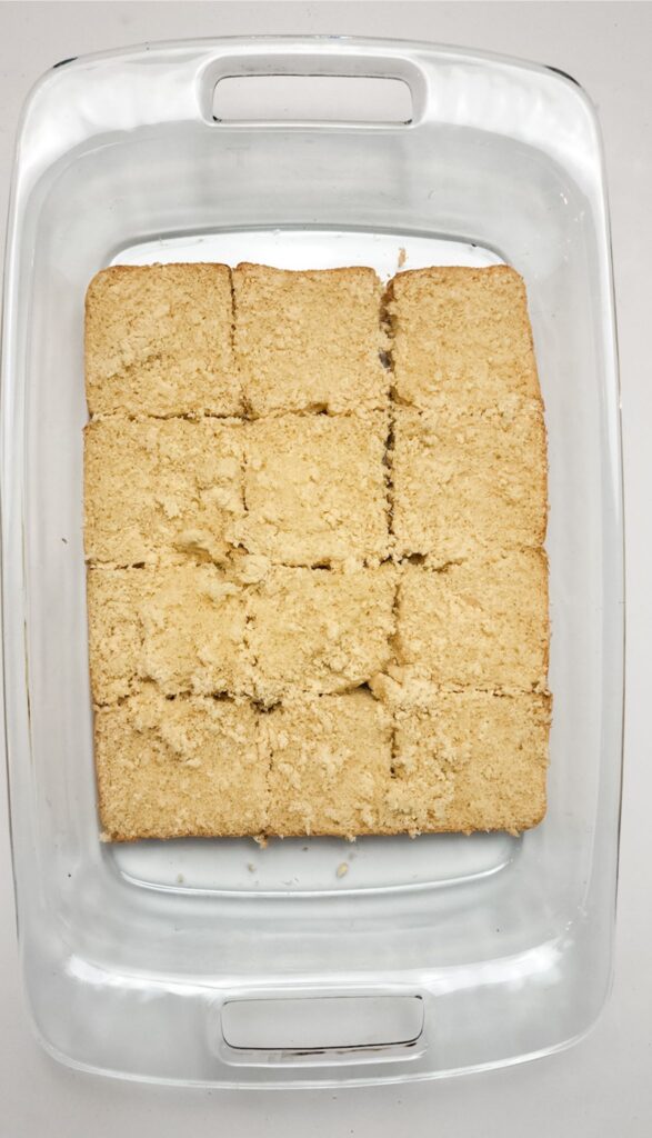 Easy Italian Sliders Recipe 3 A glass dish containing a square, baked dessert cut into 12 pieces, viewed from above, sits tantalizingly next to a plate of Italian sliders.