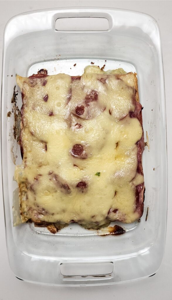 Easy Italian Sliders Recipe 6 A rectangular dish showcases baked Italian sliders topped with melted cheese and visible meat slices, reminiscent of an easy Italian sliders recipe.