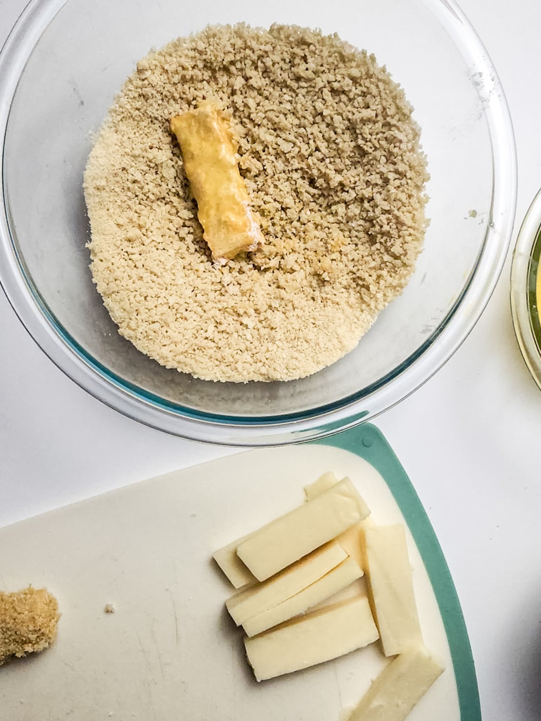 mozzarella sticks getting coated in panko breadcrumbs.