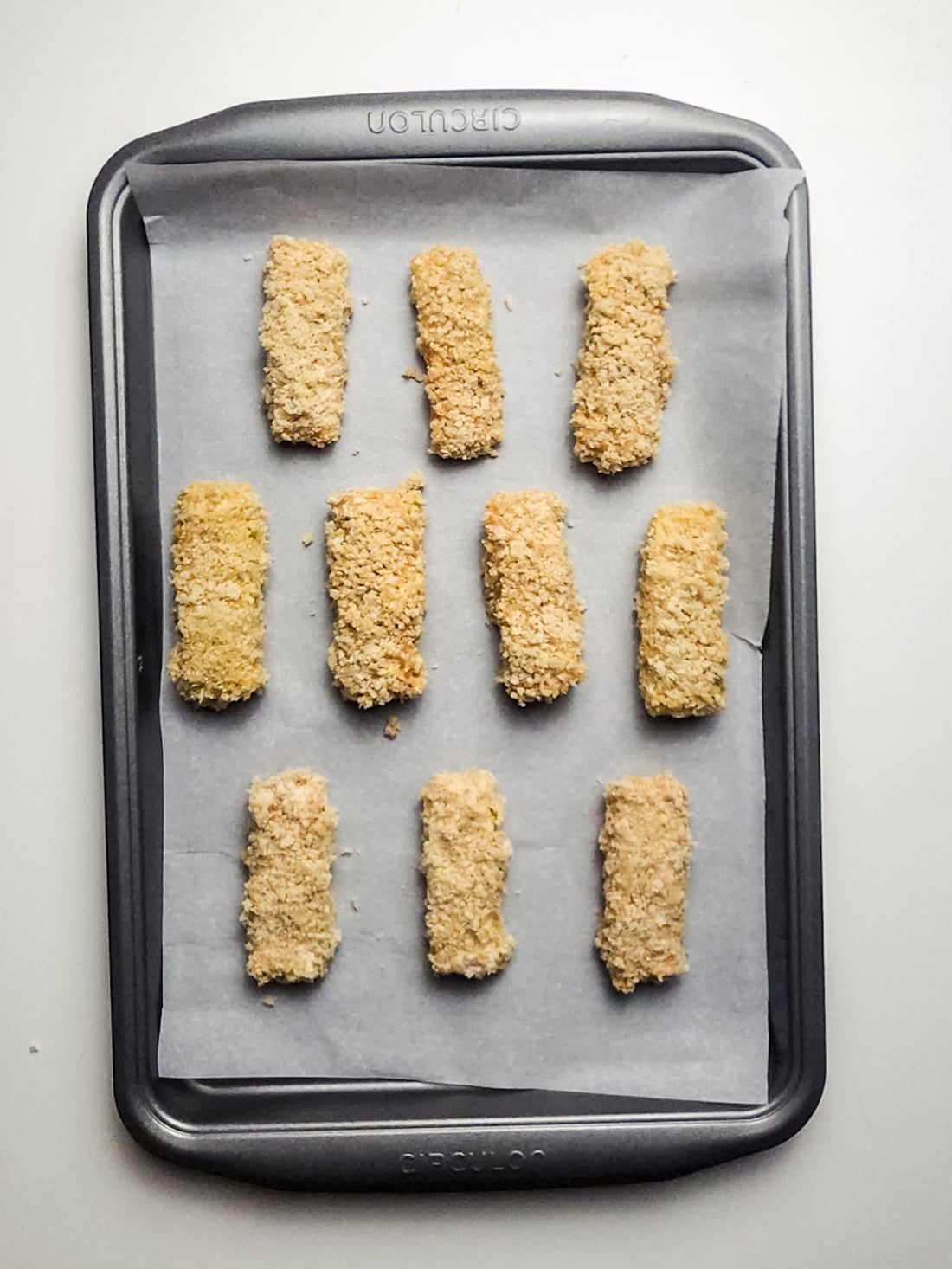 mozzarella sticks on a lined baking sheet.