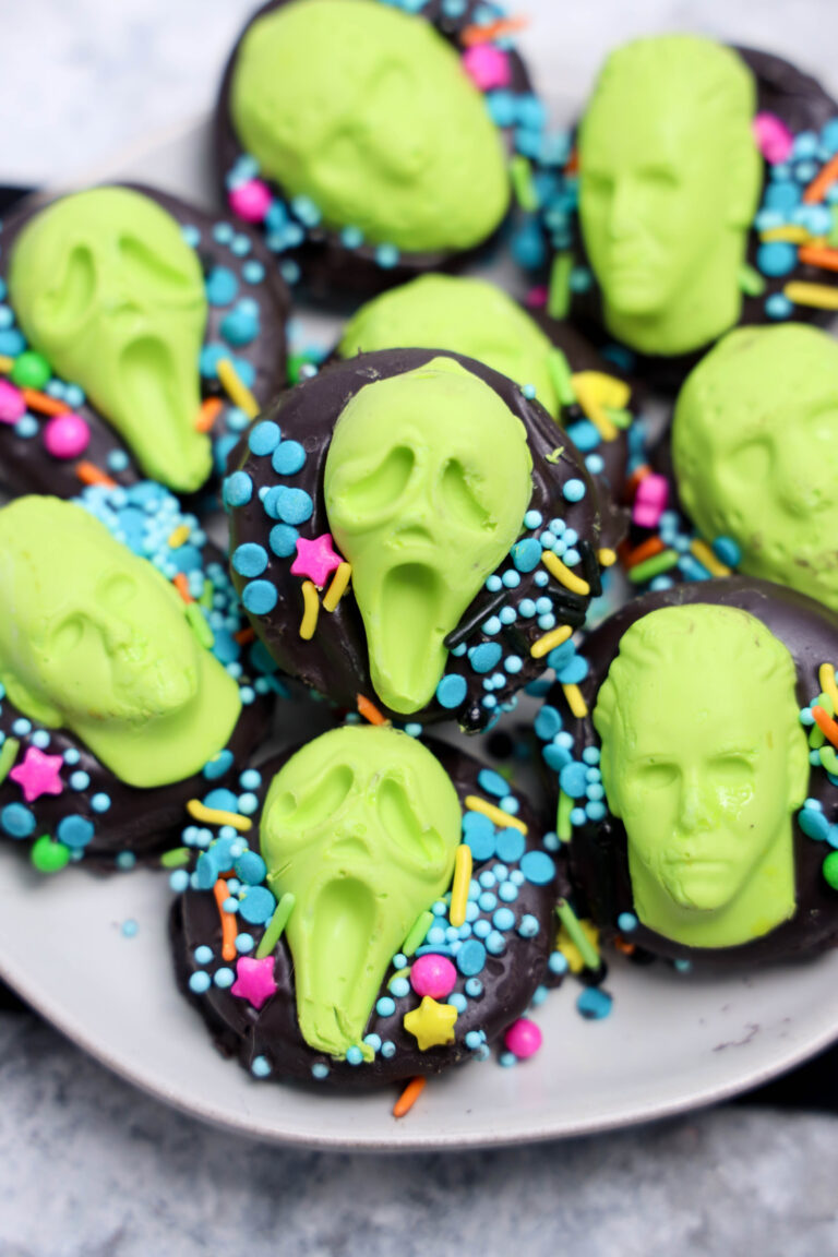 Plate of Summerween Slasher Oreos—chocolate cookies decorated with bright green candy faces, some screaming, and topped with colorful sprinkles.