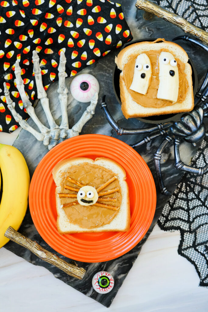 Halloween Toast That'll Make You Go BOO-nanas 10 Two slices of Halloween Toast with peanut butter are decorated as festive snacks: one as a spider with pretzel legs, the other as ghosts made from banana slices and chocolate chips for spooky faces.