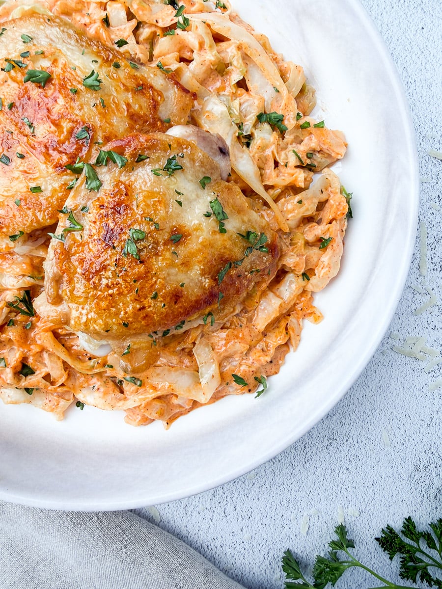 a plate with cabbage alfredo and chicken thighs on top crispy