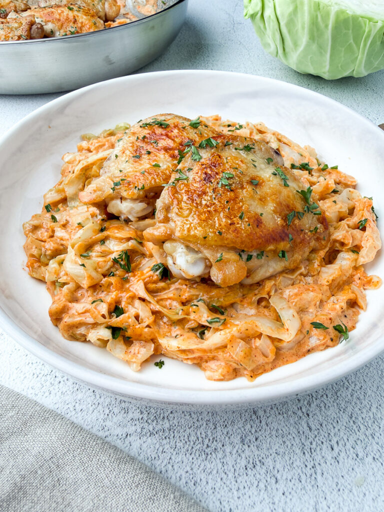Creamy Cabbage Alfredo with Crispy Chicken thighs in a plate on table