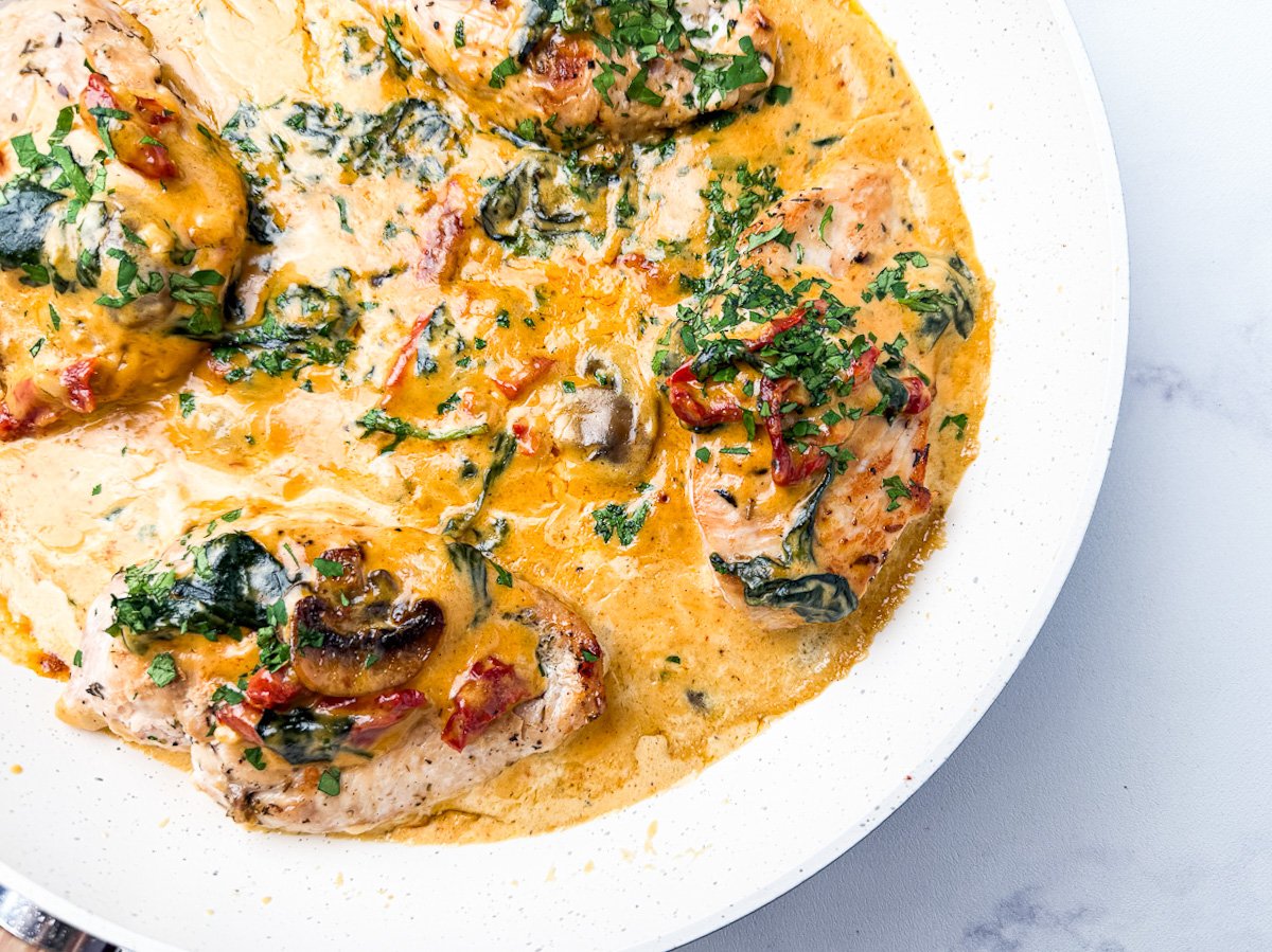 Creamy Tuscan Chicken in a plate with sauce and parsley