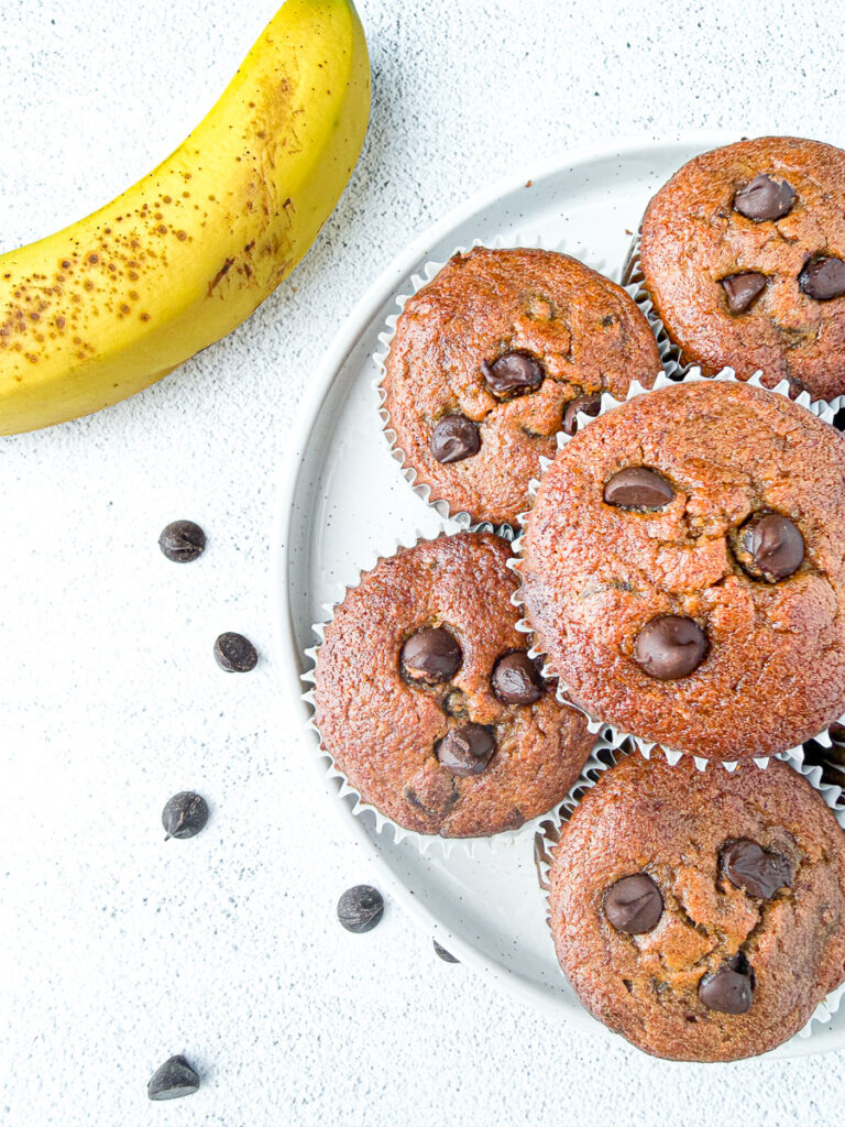 Healthy Almond Butter Banana Chocolate Chip Muffins on plate with banana