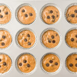 Healthy Almond Butter Banana Chocolate Chip Muffins in muffin pan with chocolate chips on top