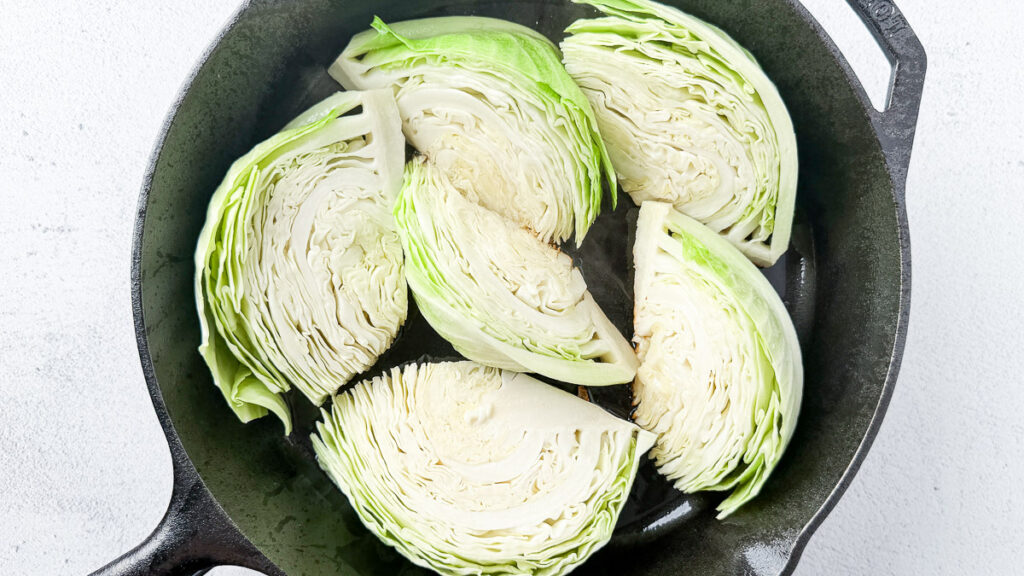 Pan-Seared Cabbage Wedges with Miso-Honey Glaze 6 cut cabbage wedges in cast iron skillet for pan-seared cabbage wedges with miso-honey glaze recipe