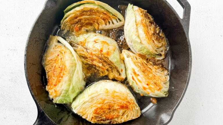 Pan-Seared Cabbage Wedges with Miso-Honey Glaze 15 cabbage wedges with miso honey sauce on top in cast iron skillet