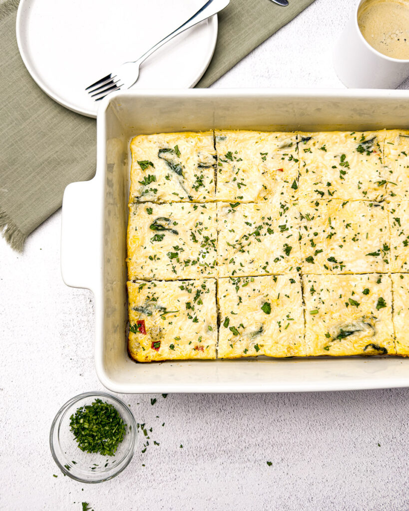 Easy Sausage and Egg Breakfast Casserole (No Bread!) 2 image of sausage and egg casserole in a pan with coffee and plate next to it