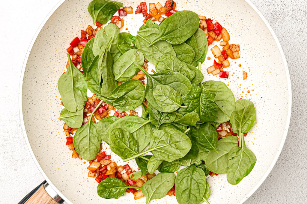 Easy Sausage and Egg Breakfast Casserole (No Bread!) 7 diced onion, bell pepper, spices, garlic and fresh spinach sautéed in white pan