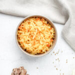 Overhead view of vibrant golden small-batch sauerkraut, colored with turmeric, served in a bowl on a light countertop.