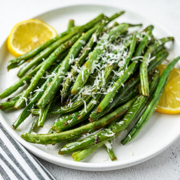ghee garlic green beans with Parmesan on plate with lemon slices