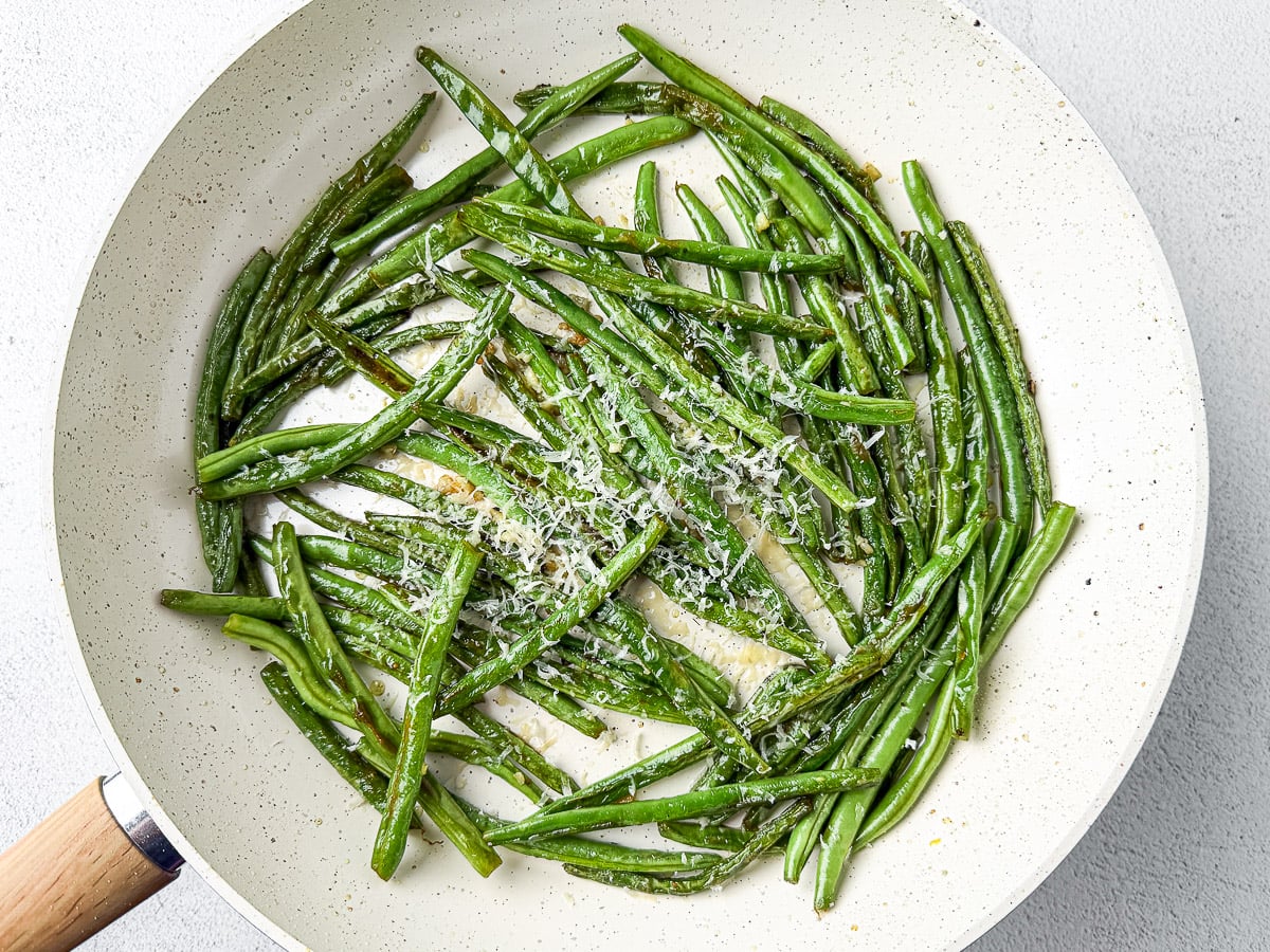 Squeezing Fresh Lemon Juice and sprinkling Parmesan Over The Garlic Green Beans.