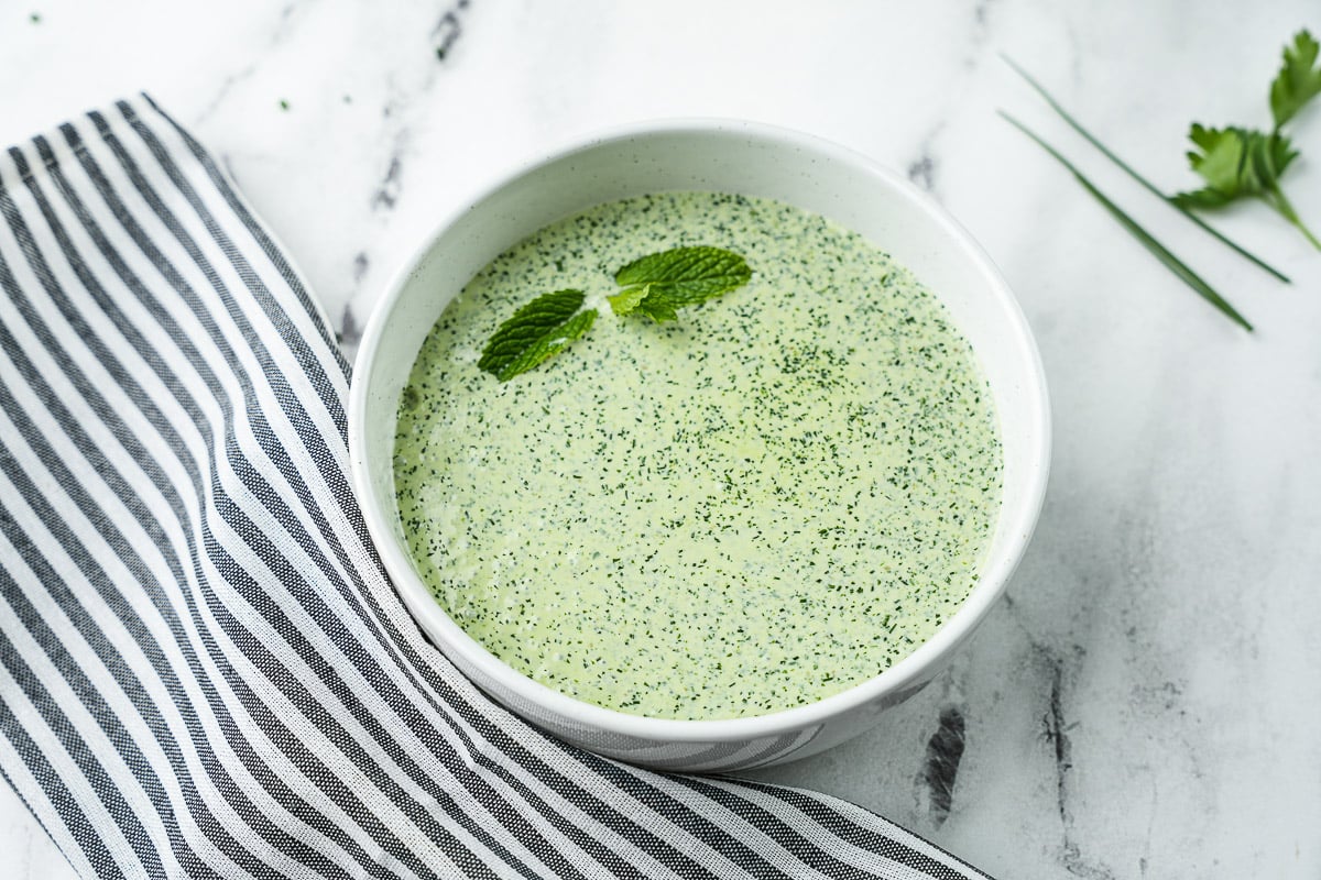 Green goddess dressing on countertop in white bowl