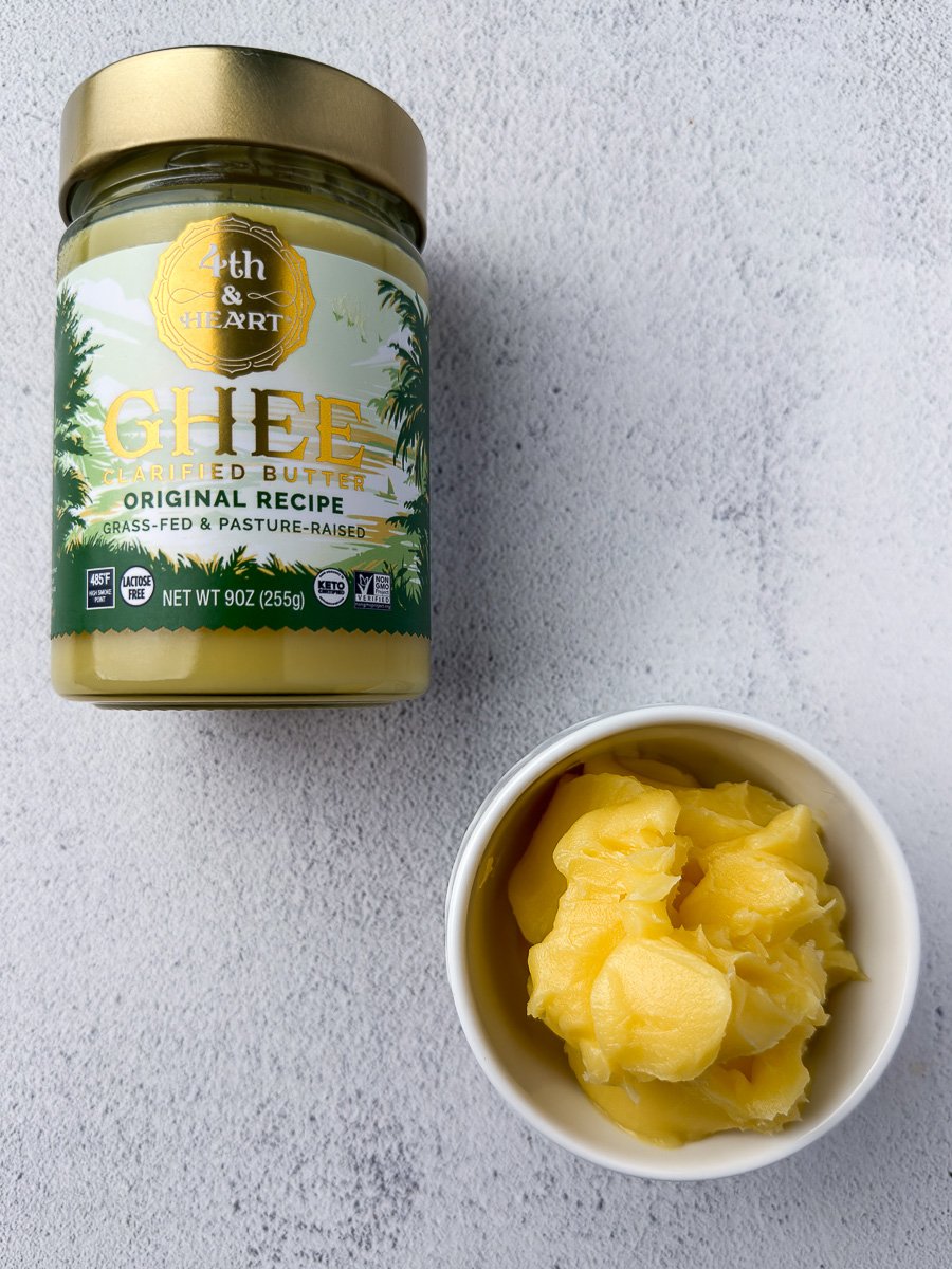 Ghee jar next to a small white bowl with ghee on countertop