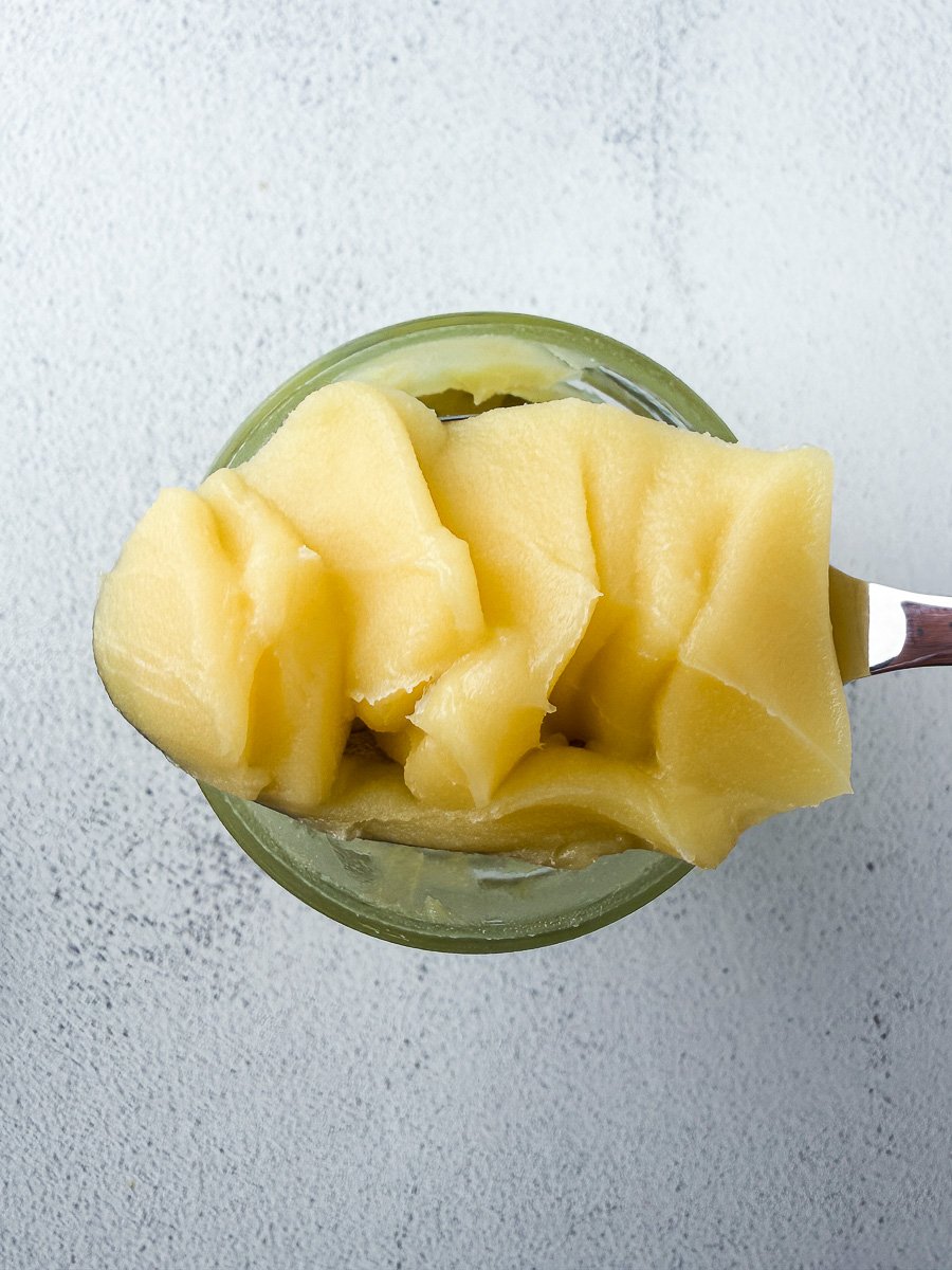 Ghee scooped in spoon over glass jar