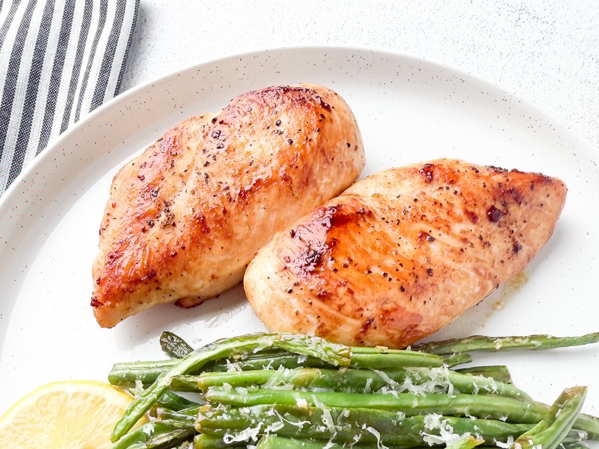 chicken breast seared in ghee on white plate with green beans