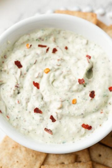 Roasted garlic cottage cheese dip in white dip bowl with crackers