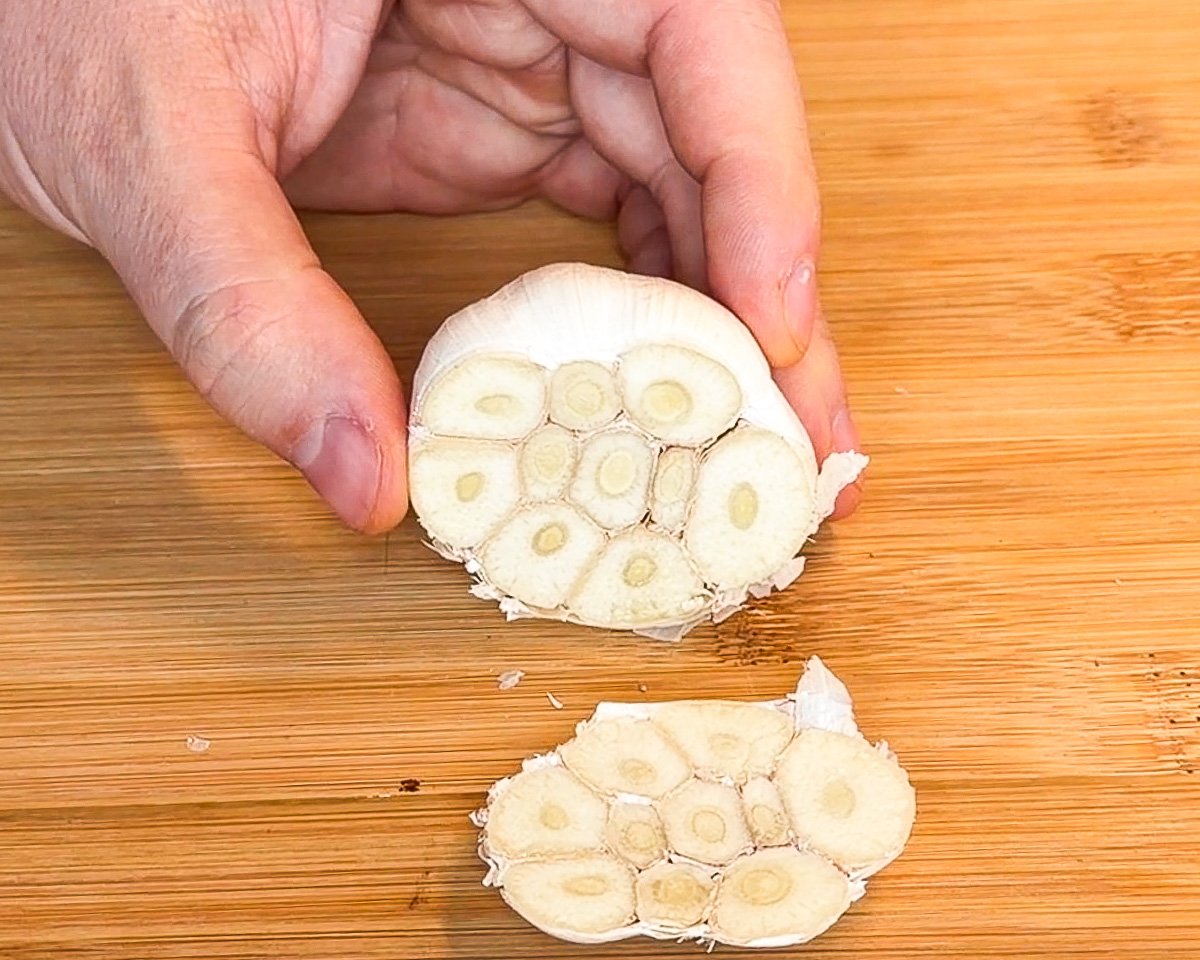 cut garlic bulb on wooden cutting board